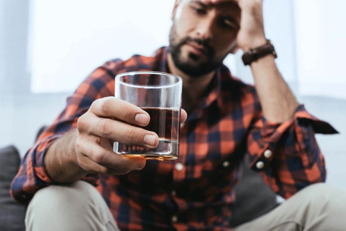 man staring at glass wondering am i an alcoholic
